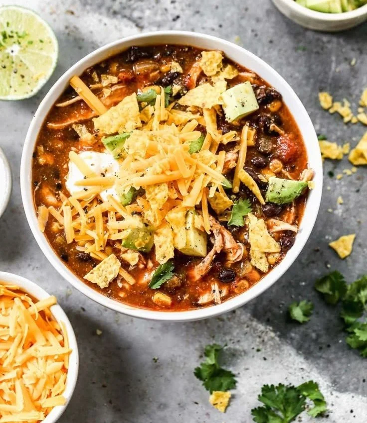 Bowl of easy, low-calorie crockpot chicken enchilada soup with toppings.