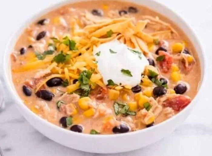Bowl of slow cooker chicken enchilada soup garnished with cilantro and cheese
